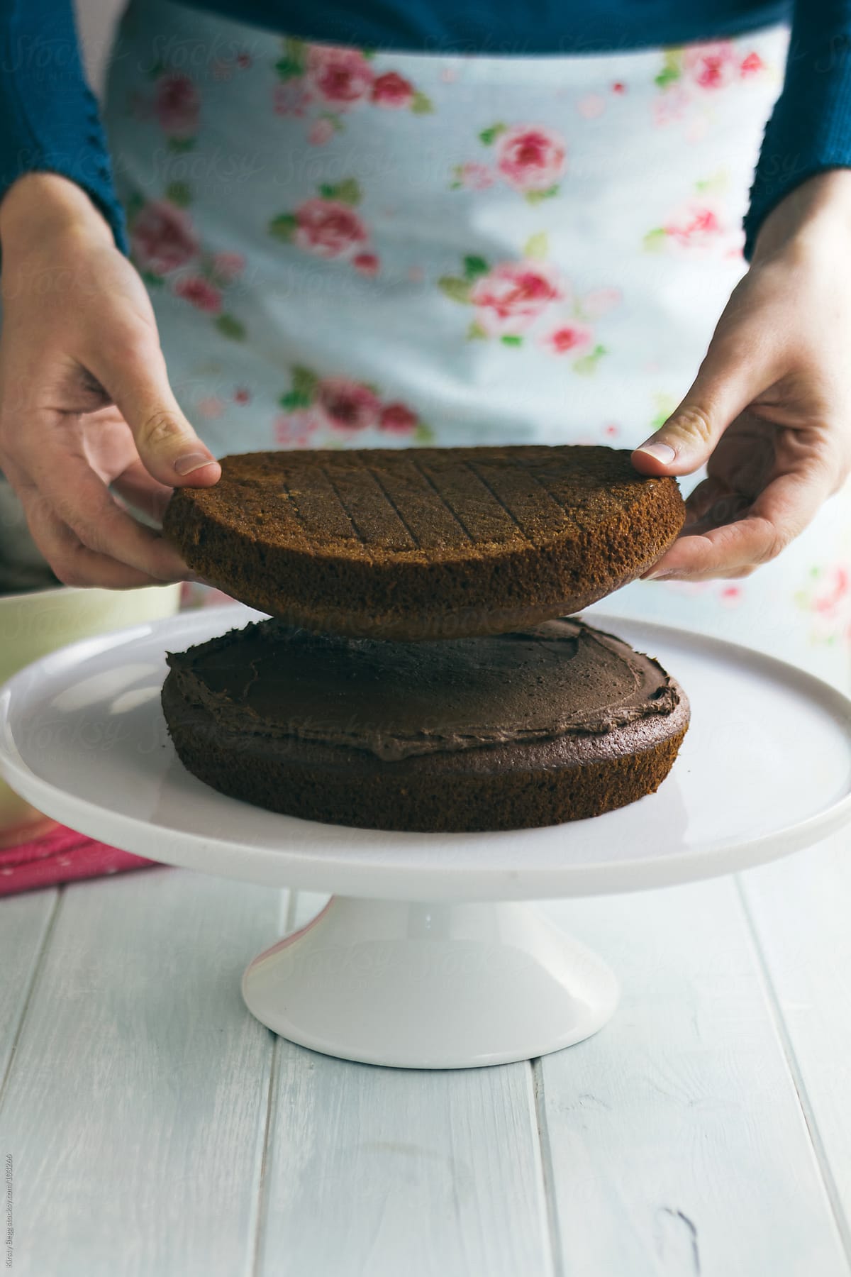 Woman adding second layer to chocolate cake