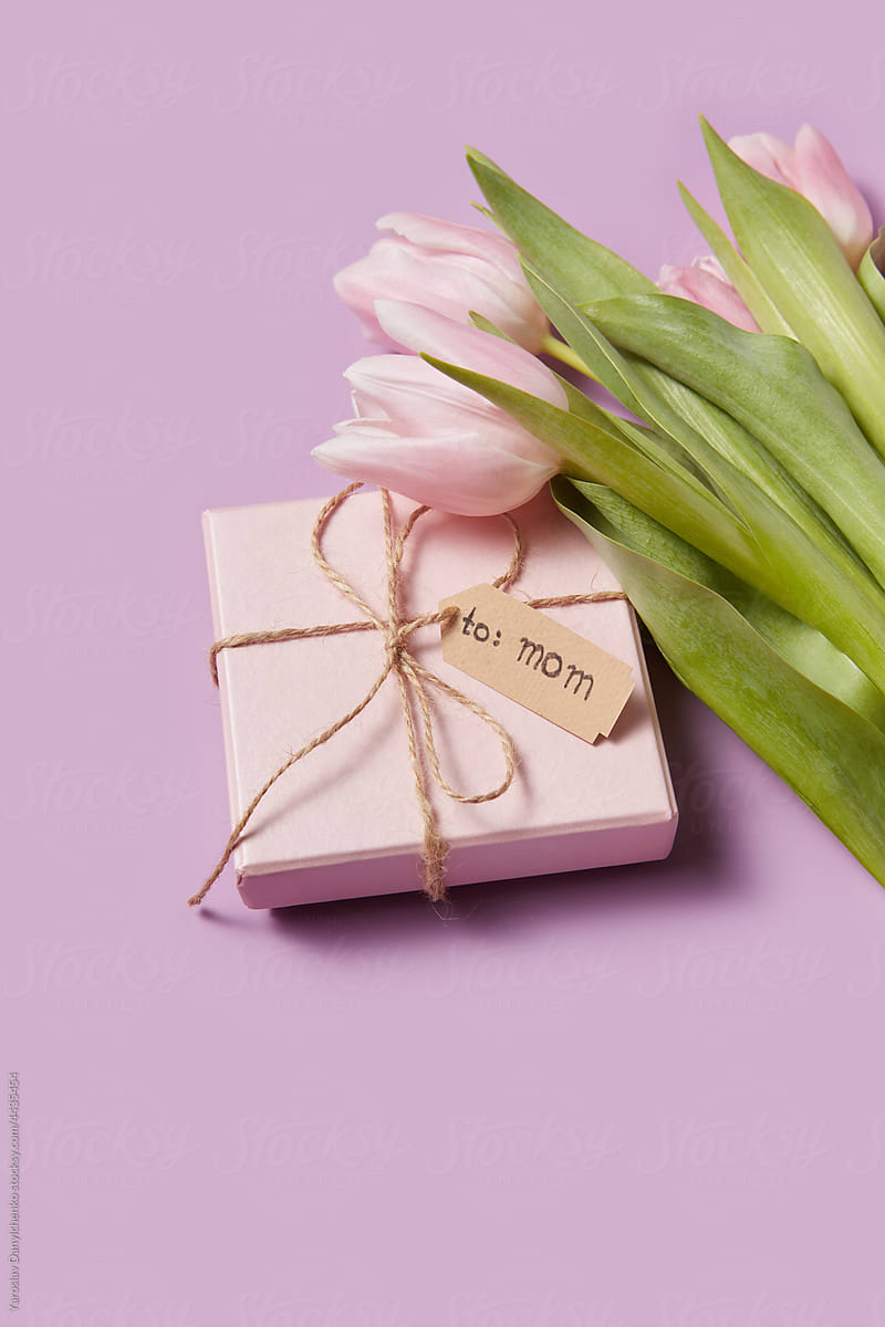 Gift box and bouquet of tulips over pink background