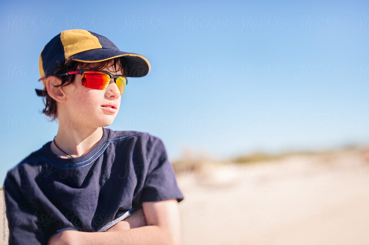 Boy with cap and sunglasses at the beach on a sunny afternoon