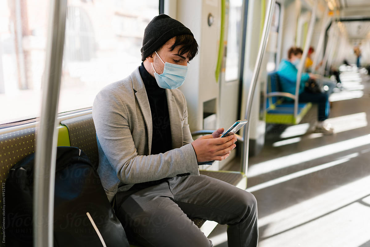 Man in face mask texting on cellphone in train