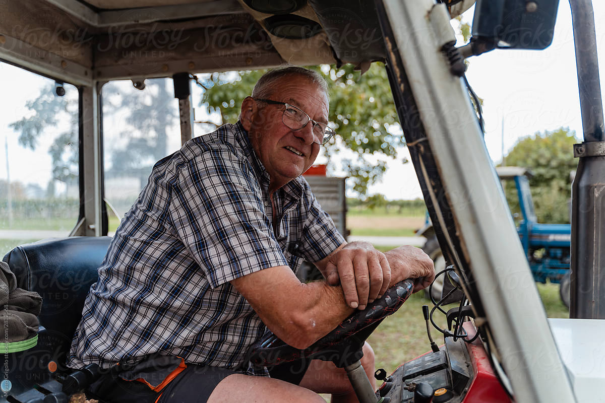 A happy farmer sits on his tractor
