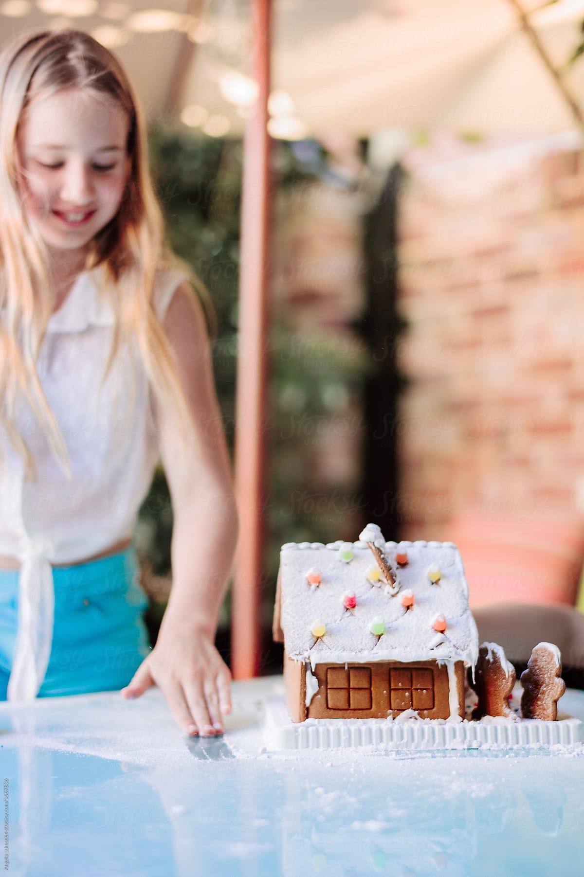 Tween girl with a gingerbread house at christmas