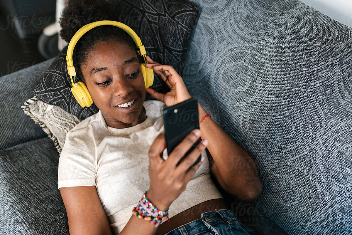 Black teenager in headphones scrolling social media