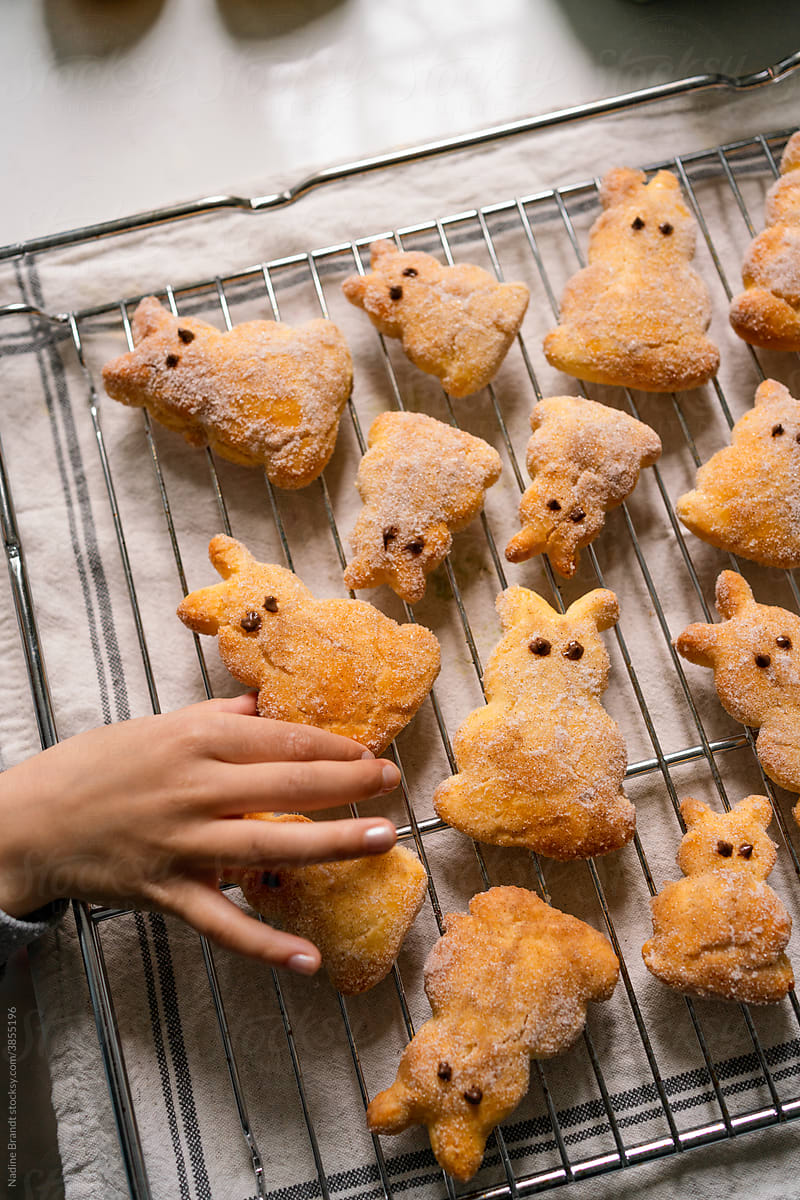 Kids hand reaching for Easter bunny pastries on baking tray