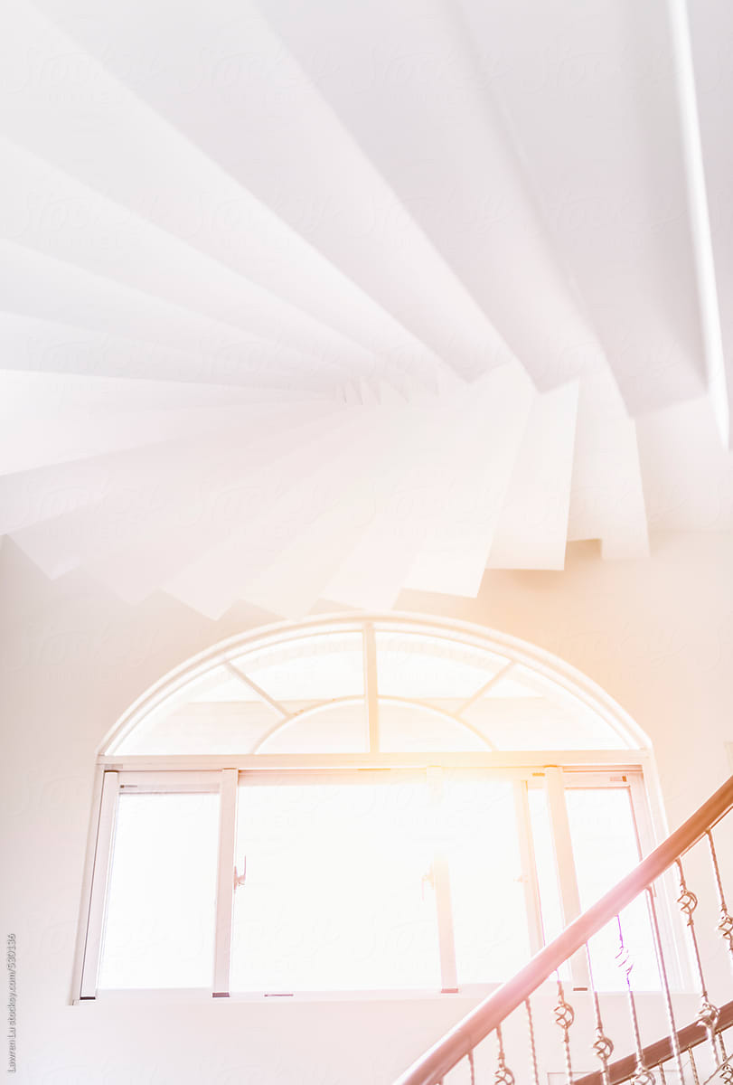 White interior spiral staircase with iron balustrade.