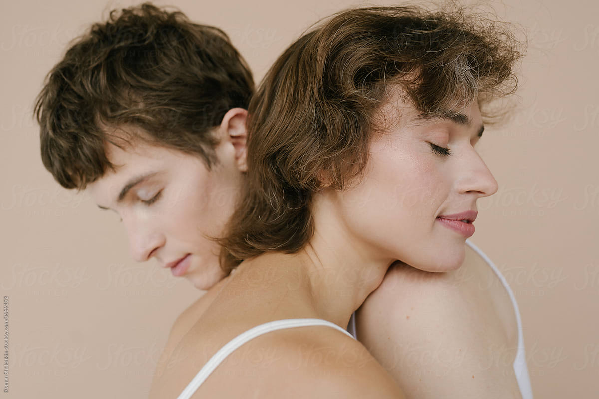 Tender young woman and androgynous man embracing in studio