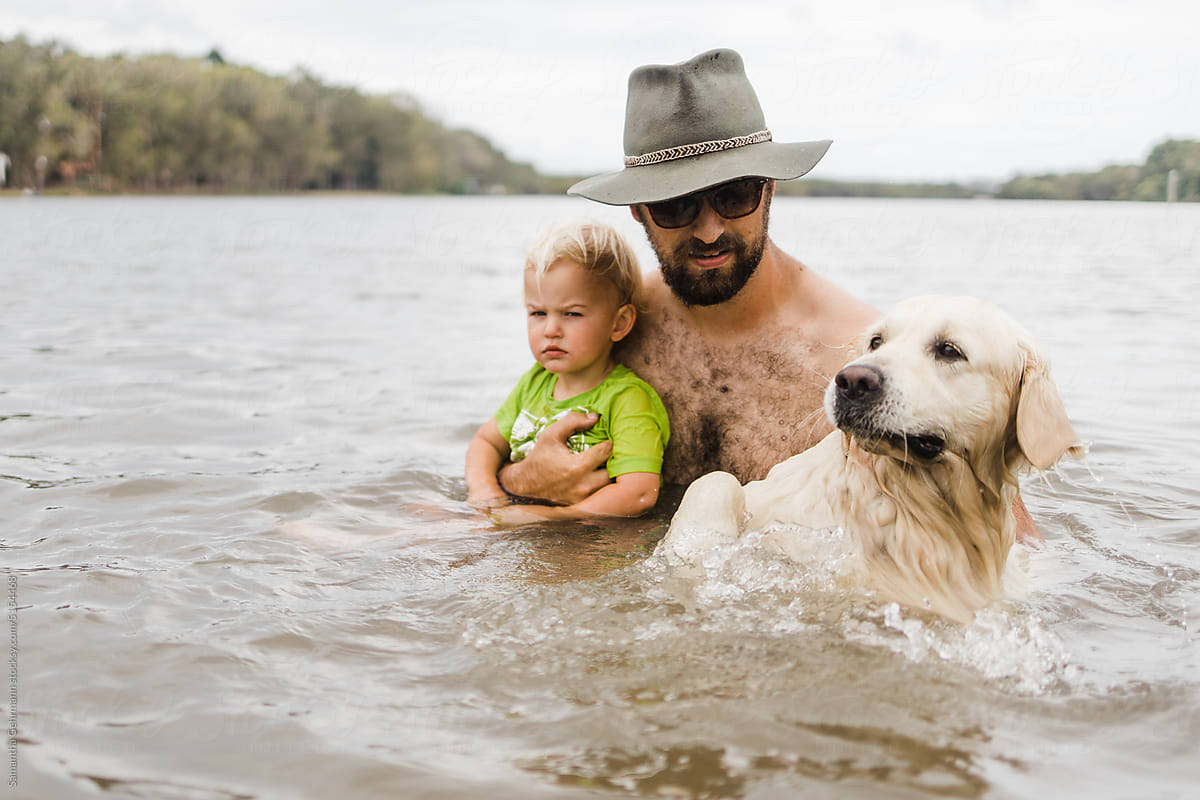 man supports his son and dog in water