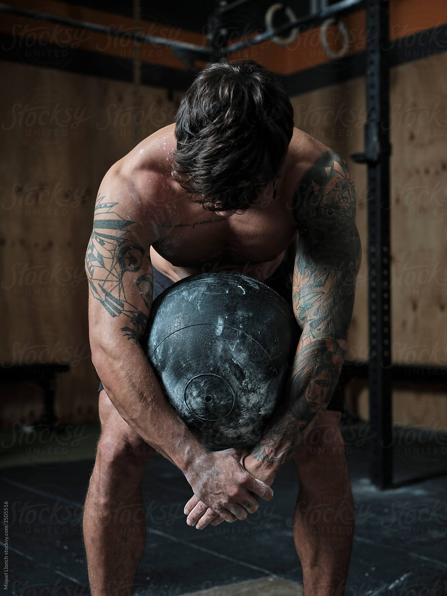 Fit man holding a weight ball in the gym