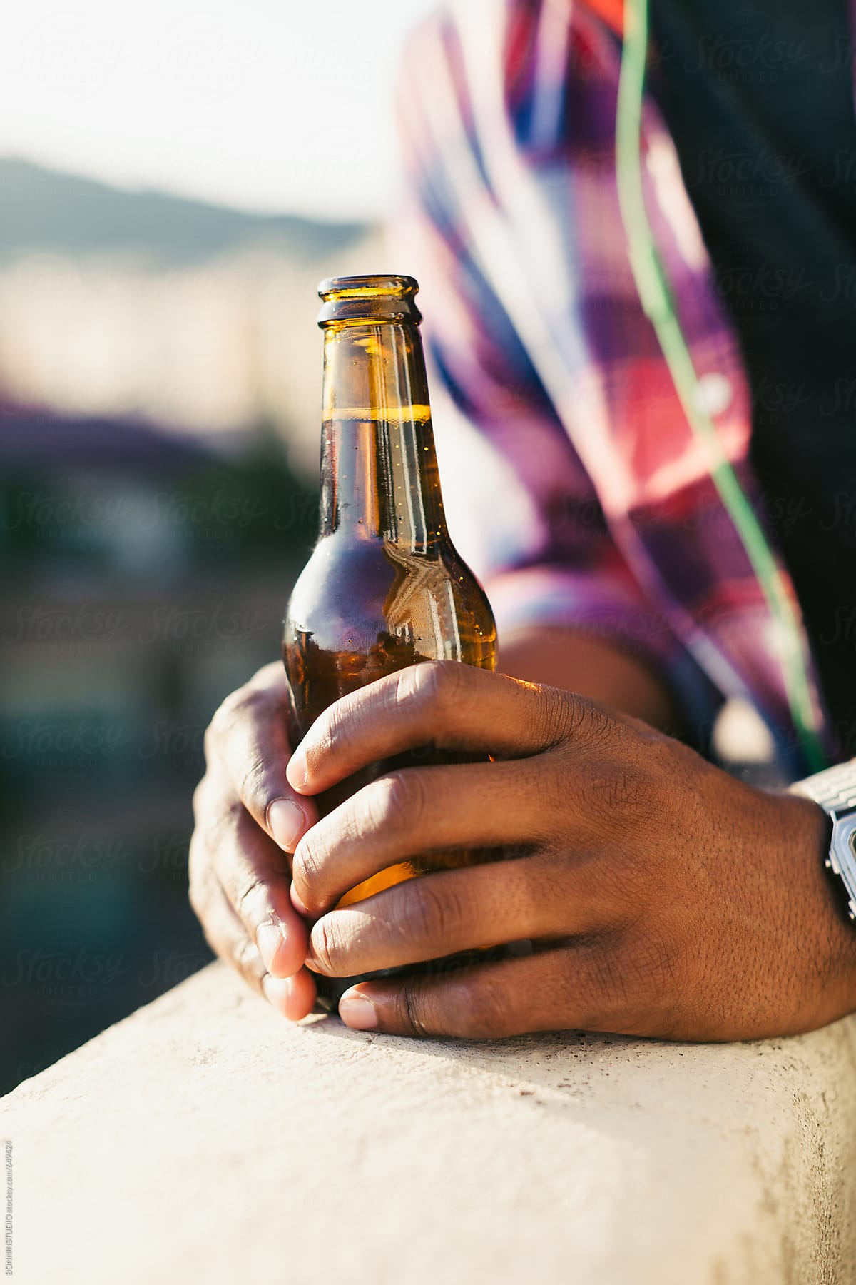 Closeup of hands holding a fresh beer on a terrace.