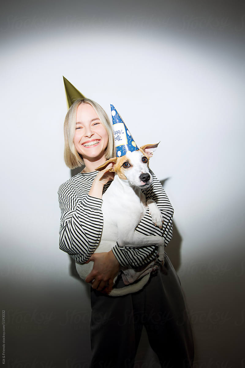 Young Female Owner Hugging A Dog In A Party Hat