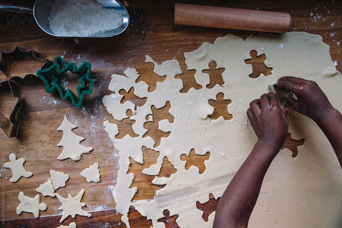African American girl\'s hands cutting ginger bread man shapes on a cookie dough