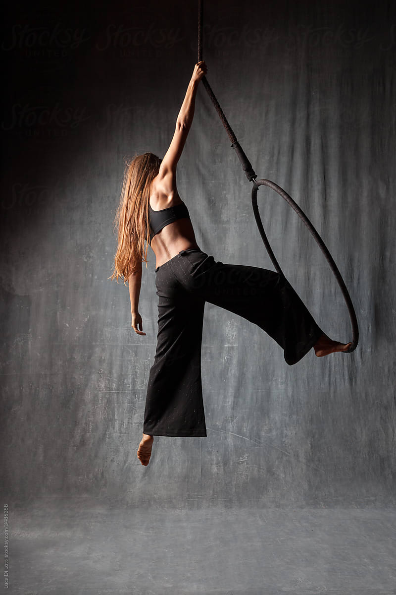Aerial artist in a beautiful pose holding on a Lyra or Aerial hoop