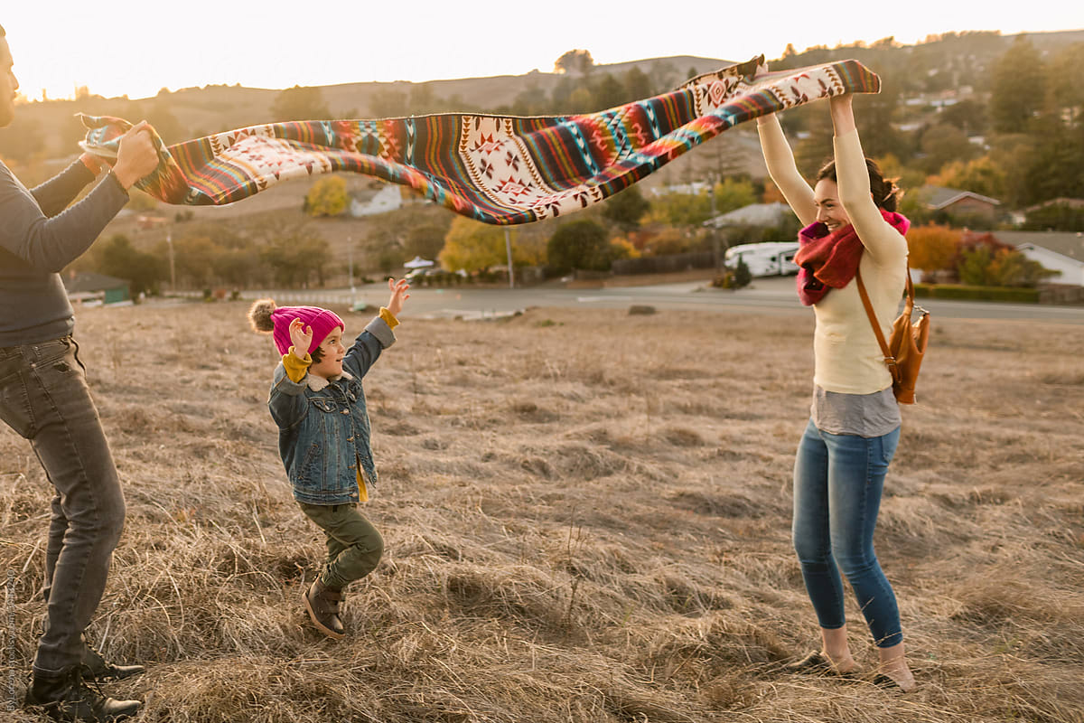 Family with ethnic blanket having fun at field