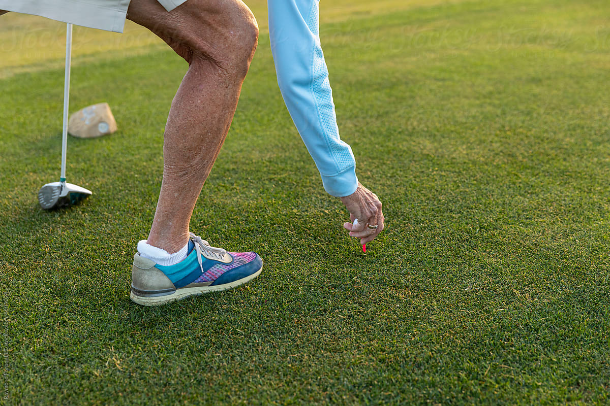 Active healthy Senior Citizen Woman puts golf ball on tee