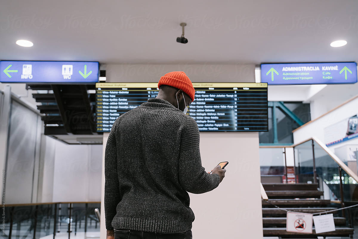 Black Man Wearing Face Mask Using Cellphone At Station