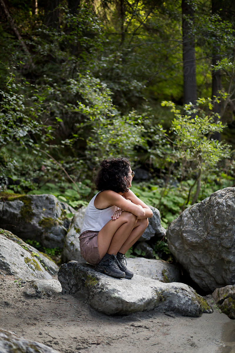 young woman in shorts sitting on a stone.