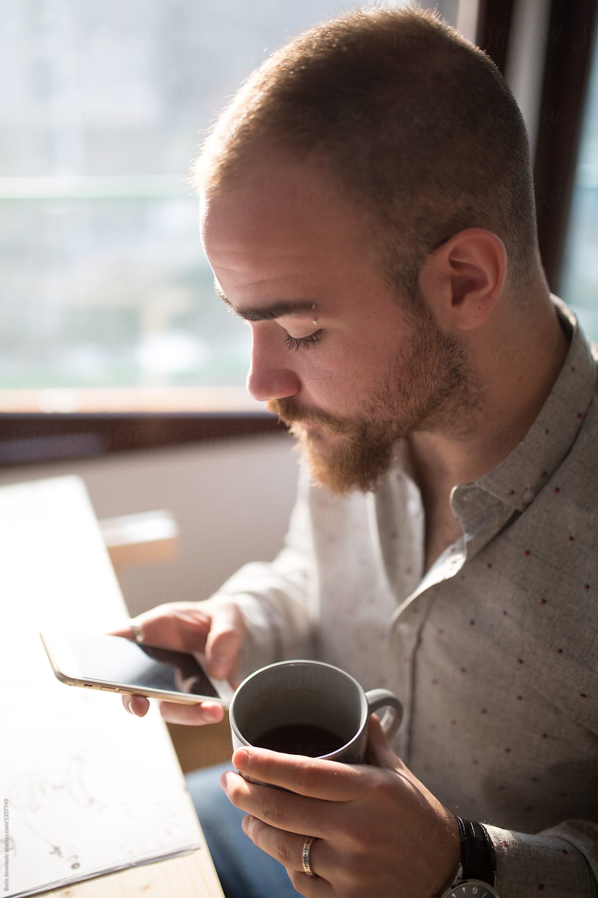 Graphic Designer Using His Phone And Drinking Coffee