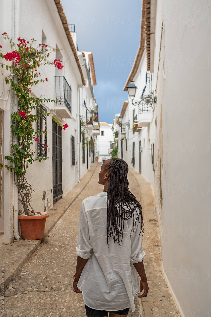 Black woman walking on cobblestone path in town