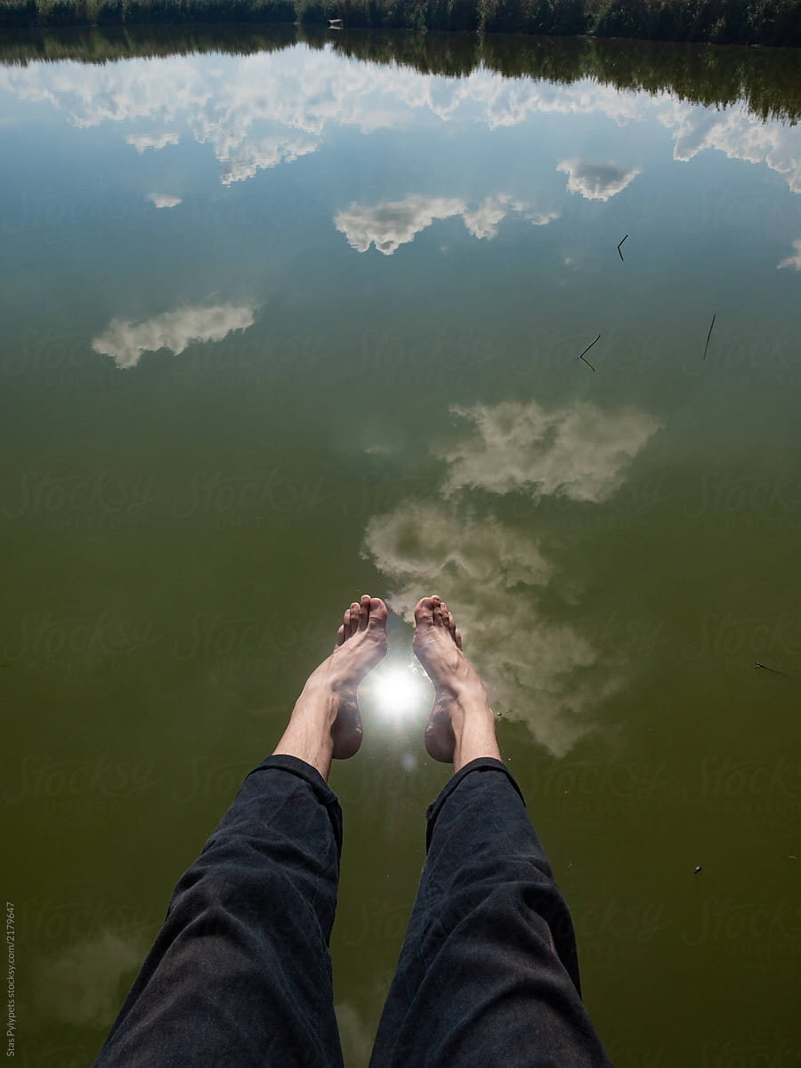 Human legs against the sky reflecting in the water