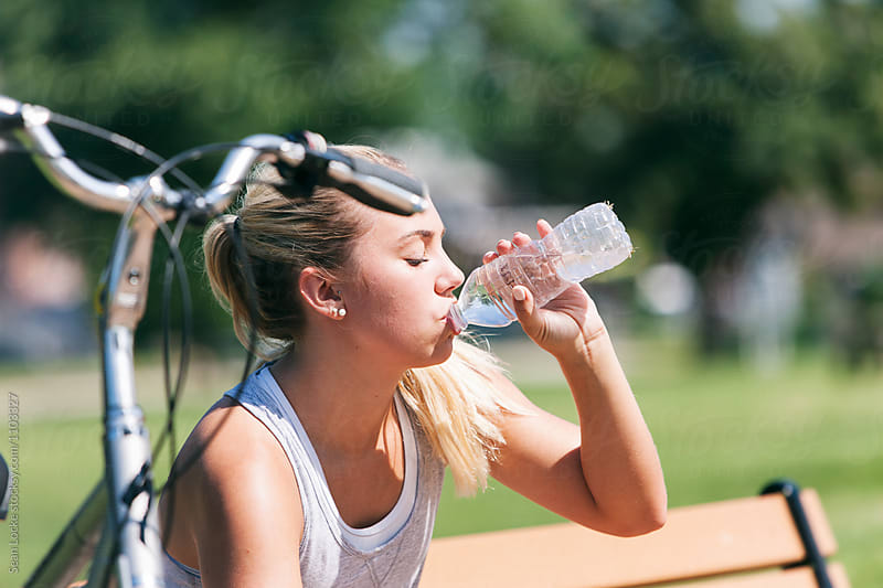 Exercise: Woman Sitting On Bench Drinking From Water Bottle
