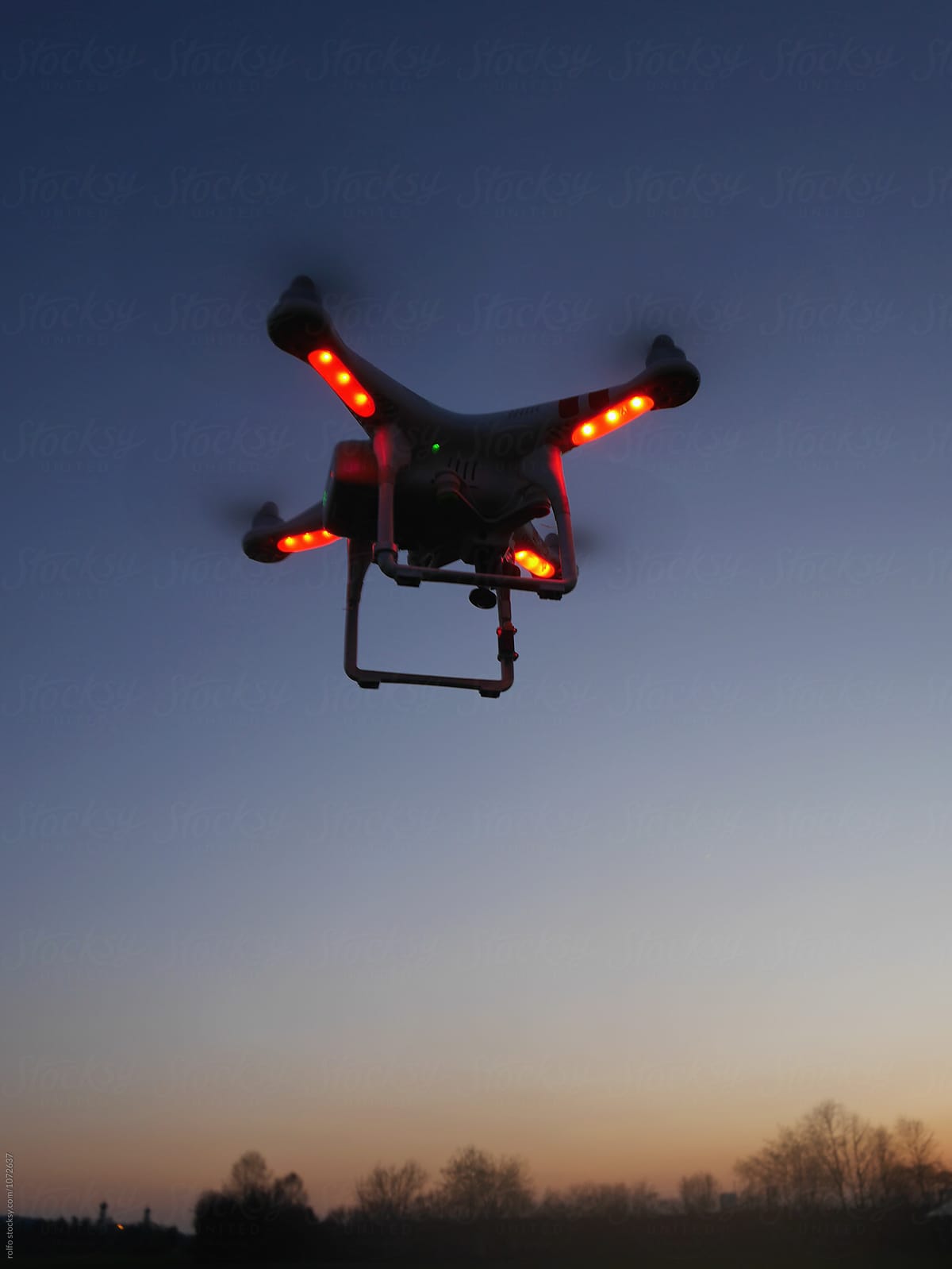 Drone with red lights against of blue sky