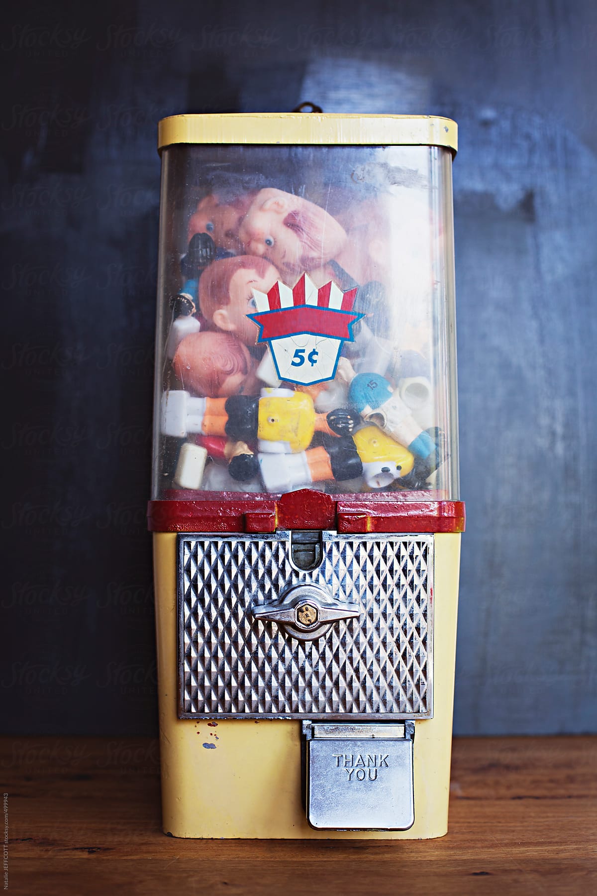 A vintage gumball machine filled with old toys and doll faces