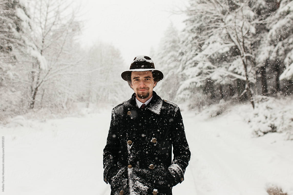 Man with a hat standing in snow