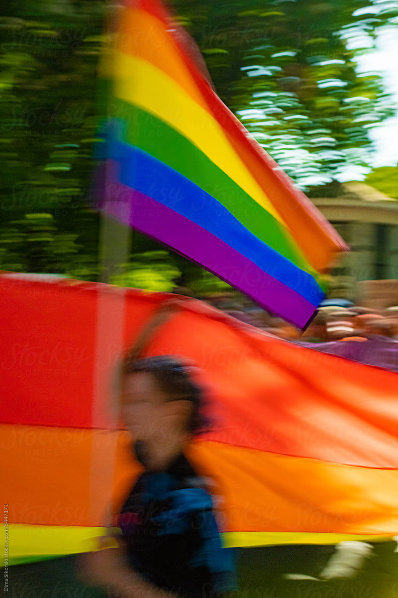 A blurred figure of a Pride parade participant with an LGBTQ flag