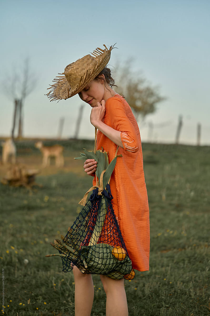 woman in a straw hat and the bag of vegetables