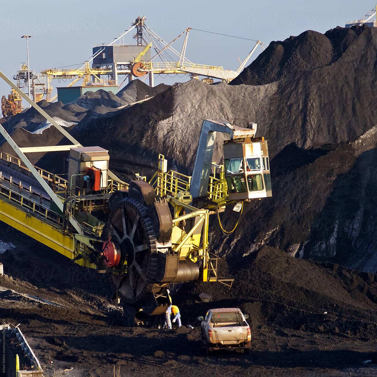 Men repairing massive coal mining machinery to dig up fossil fuels for carbon economy