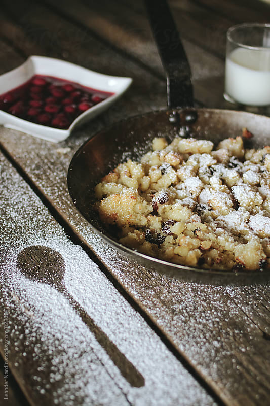 baked semolina porridge in a cast iron pan served with stewed cherries and milk