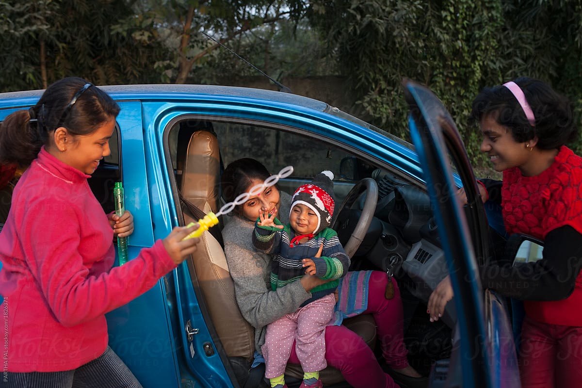 Mother and daughters sitting inside car and making fun with bubbles