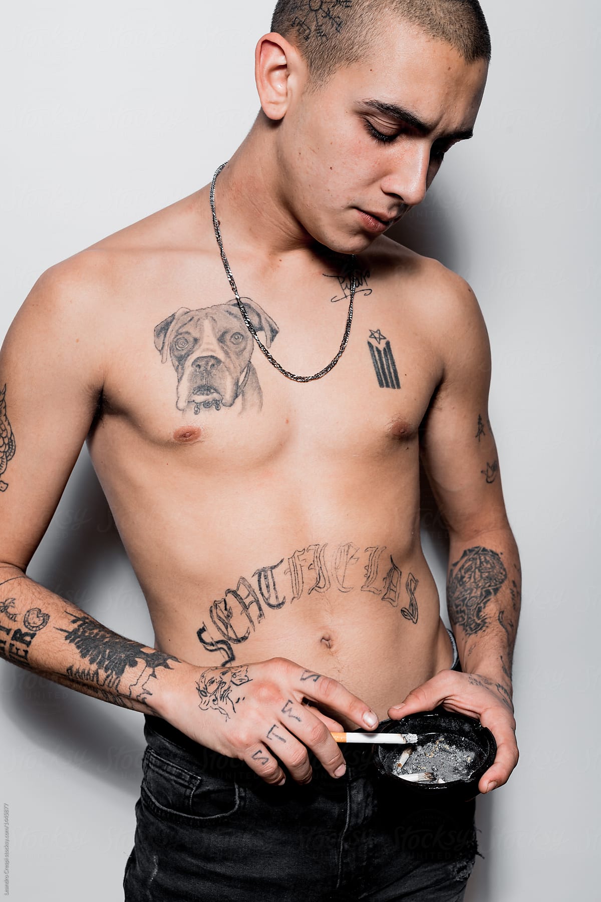 Tattooed shirtless young man portrait isolated over white wall