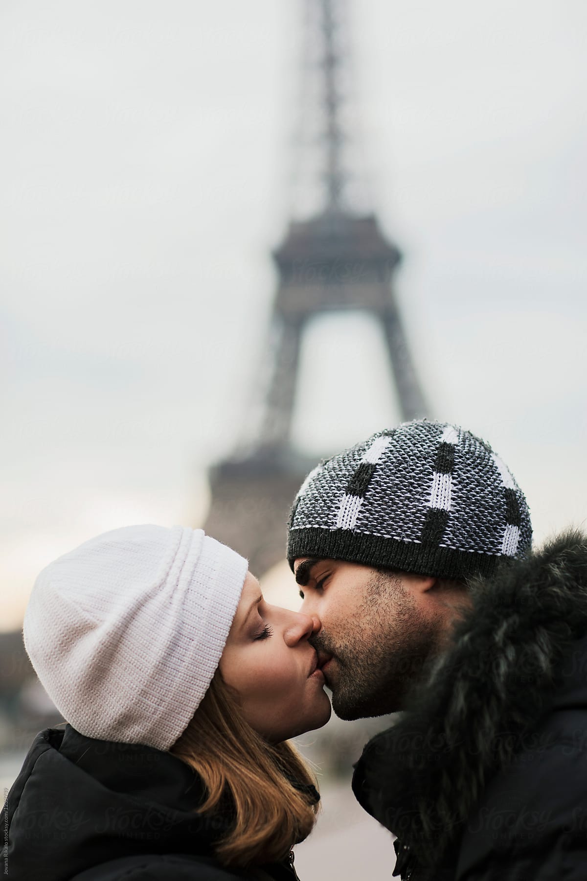 Happy couple kissing and hugging in front of the Eiffel Tower in Paris