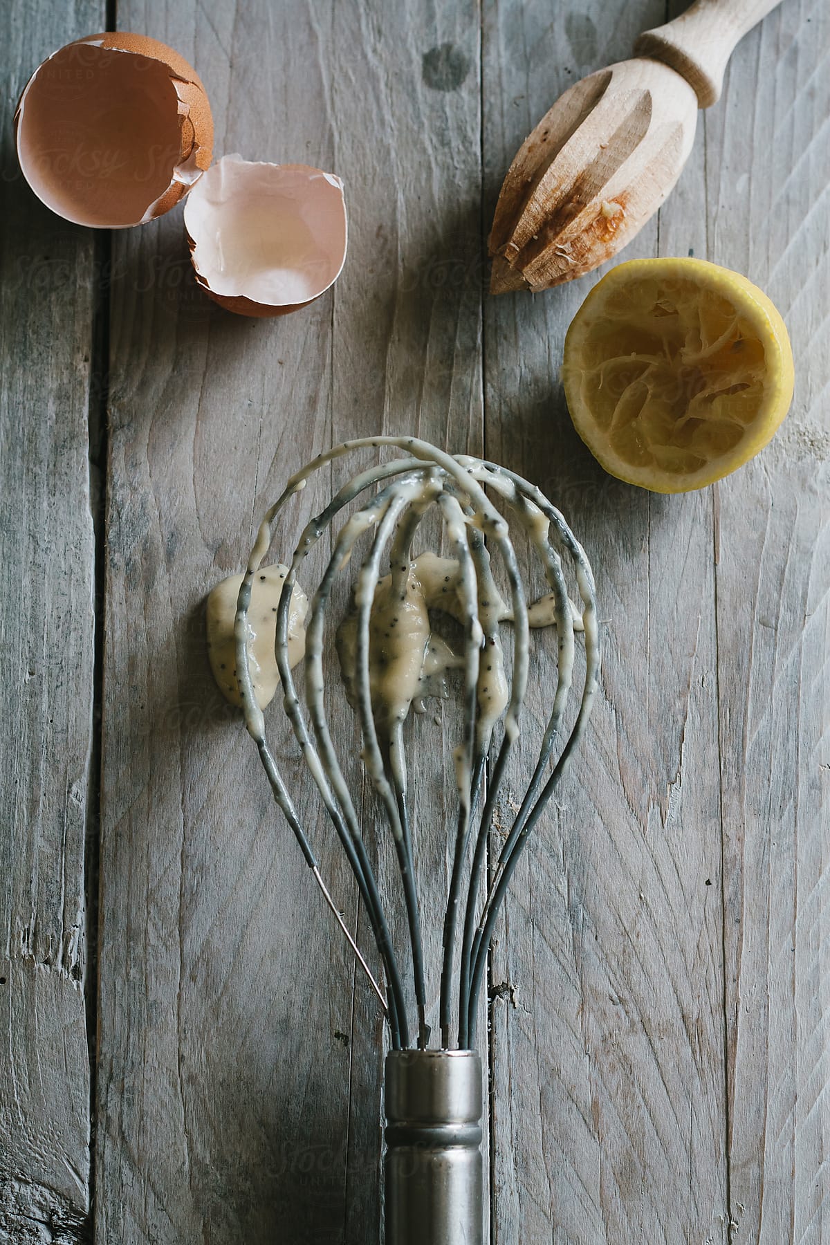 Eggs shell, juiced lemon and a whisk with batter on it.
