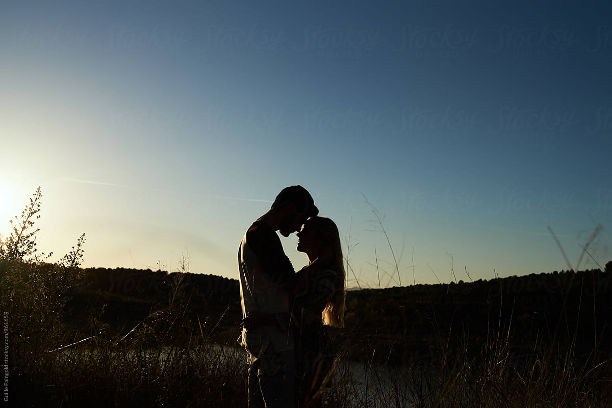 Silhouette of couple hugging against of blue sky