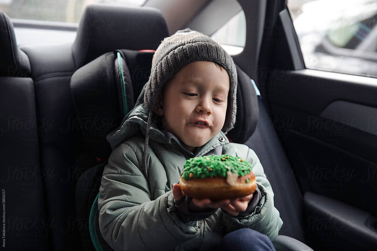 Little boy eating a donut in the car