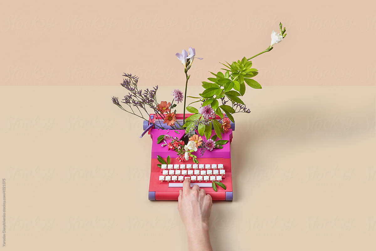 Woman typing on vintage typewriter with spring flowers