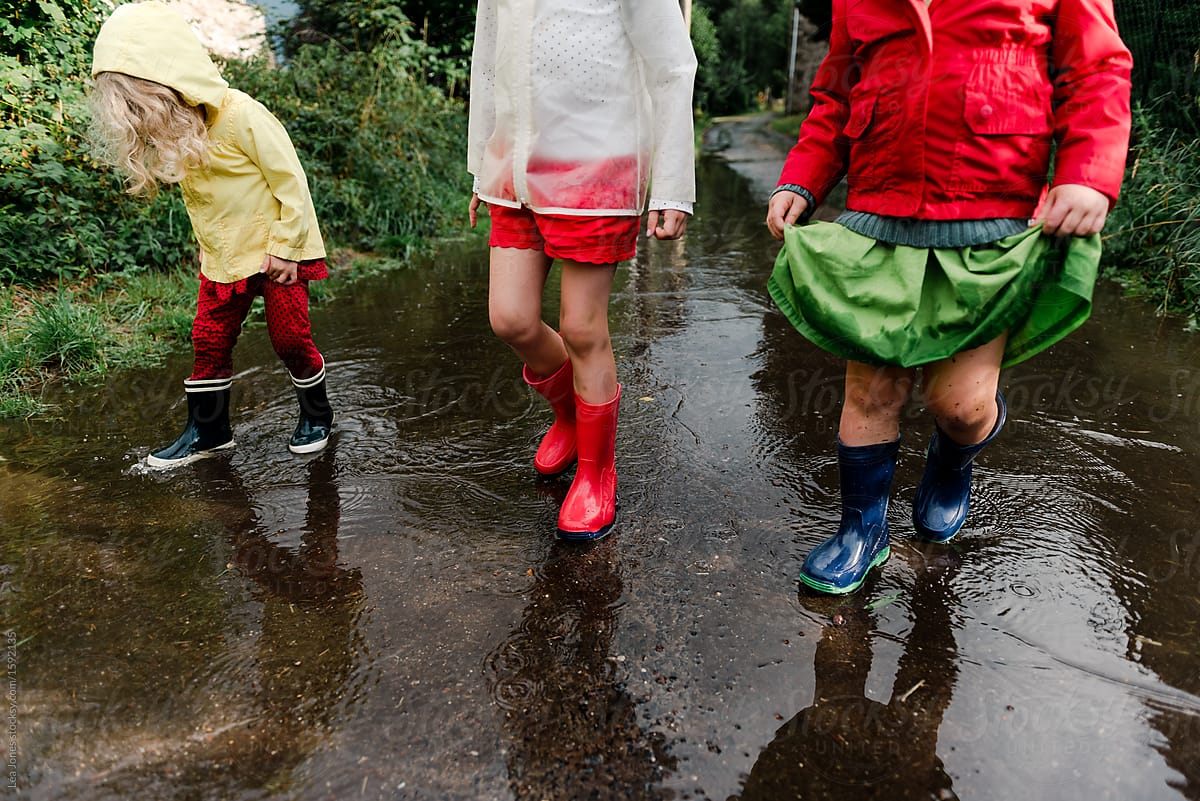 little girl jumping in puddles after the rain