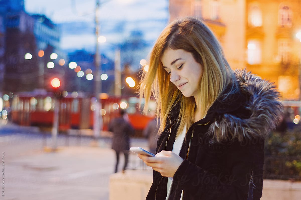 Young blond female using a smartphone on the street