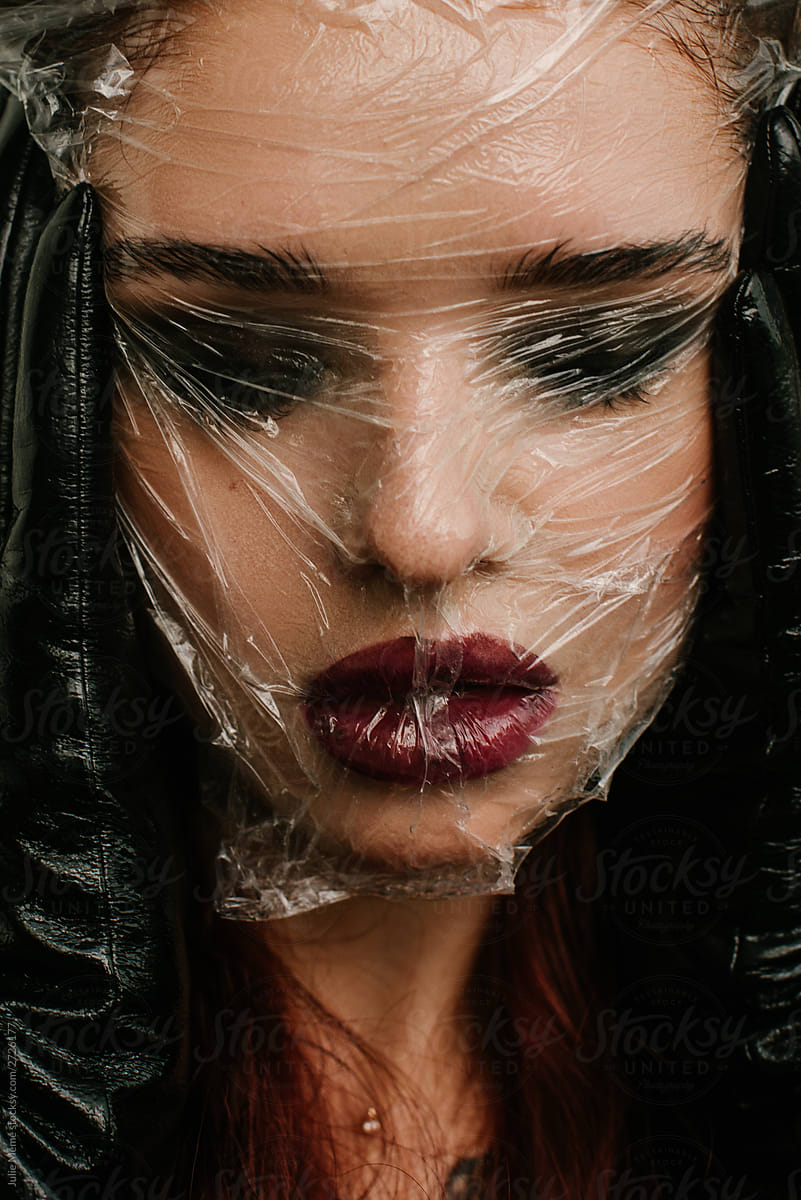 Closeup portrait of girl with dark makeup and face covered with plastic bag