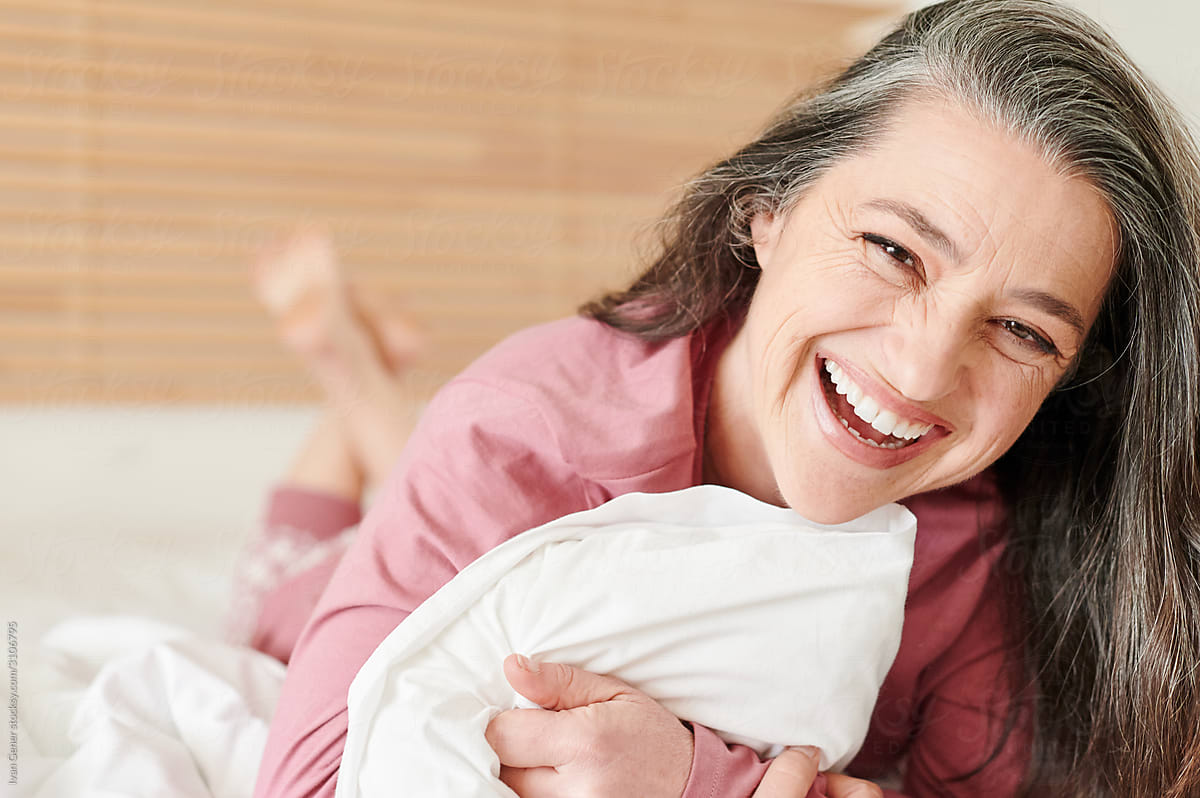 Laughing Mature Woman Lying On Her Bed By Stocksy Contributor Ivan