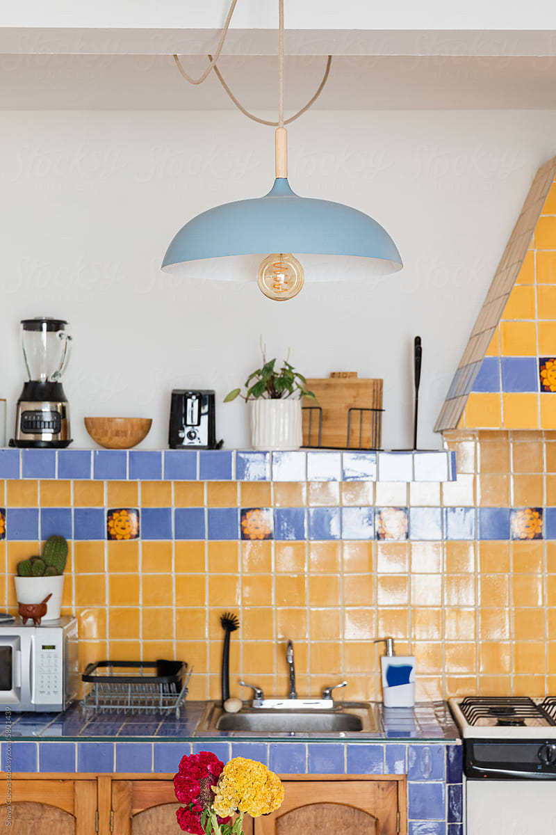 Yellow and blue tiles in a kitchen with appliances on shelves