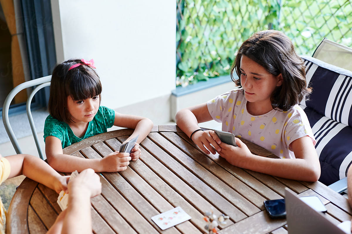 Girl playing cards with her siblings outside
