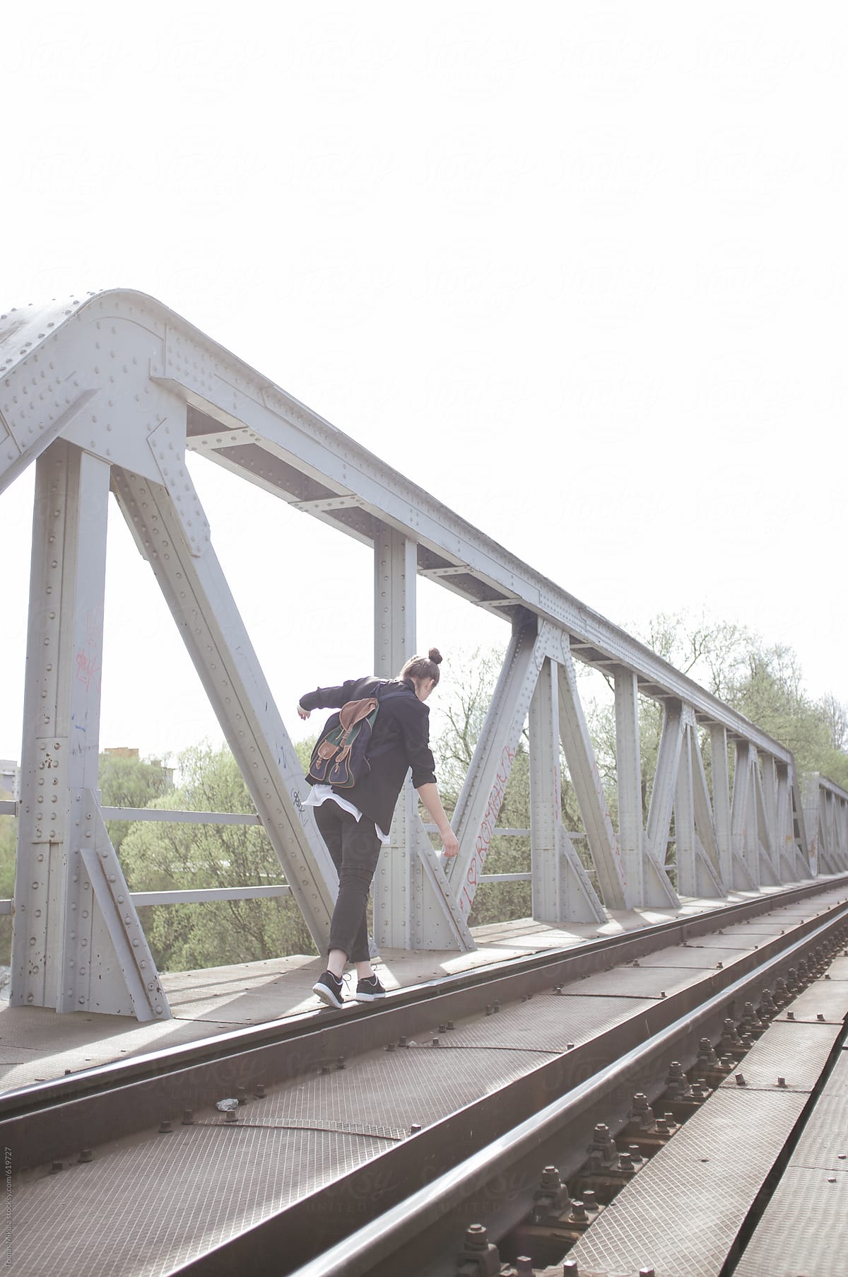Girl with retro bag walking on the train bridge
