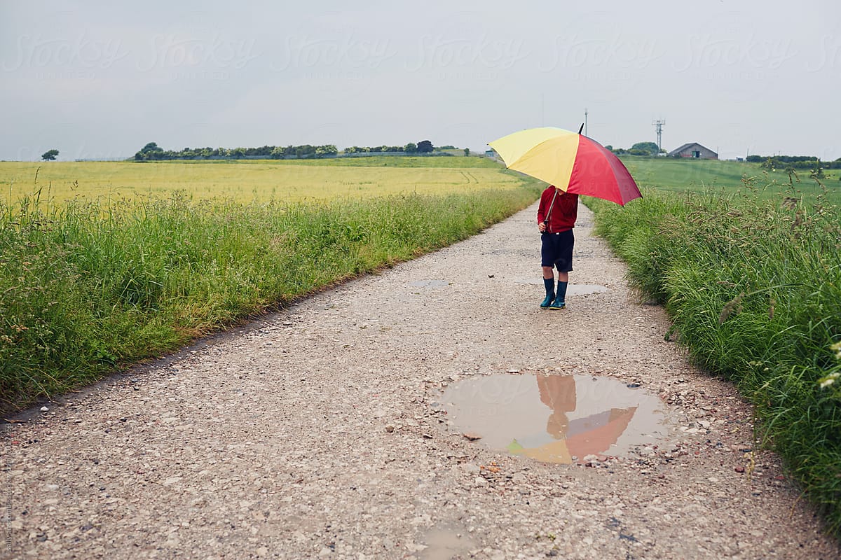 Child having fun playing outdoors on a rainy day with an umbrella