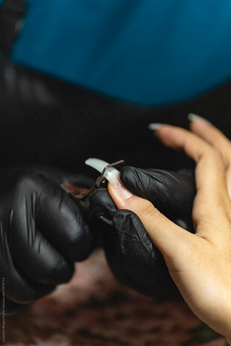Manicurist trimming the tips of her client\'s false nails