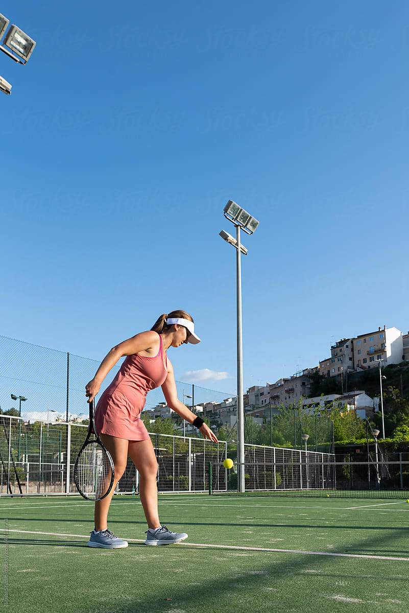 Sportswoman serving tennis ball on court