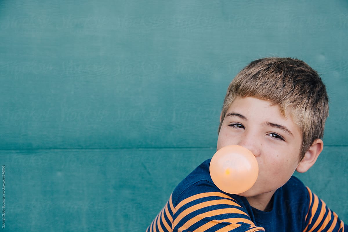 Young boy blowing orange bubble-gum bubble
