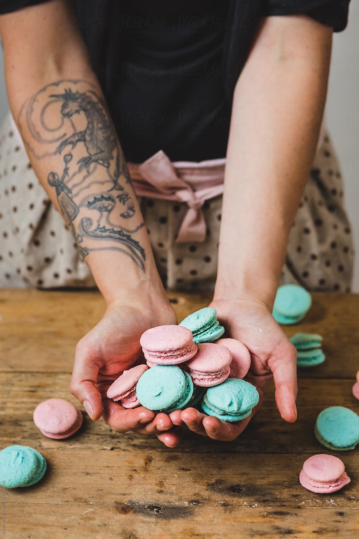 Woman Showing Colored Macarons on a Wooden Table